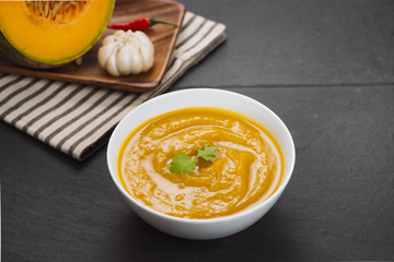Pumpkin soup in a bowl with garlic and parsley herbs