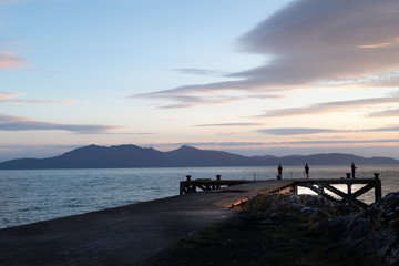 Portencross Jetty and  Hazy Arran Mountains at Sunset with Fishermen at the end of the Pier.