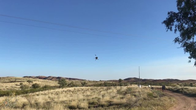 Helicopter taking off from a clearing on a sunny afternoon in the Pilbara of Western Australia