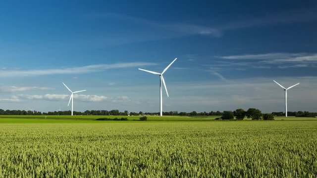 Time lapse of spinning wind turbines for electrical power generation with cloudy sky in Normandy, France. Modern technology of environment friendly energy production