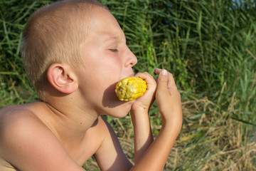 boy on the beach eating corn