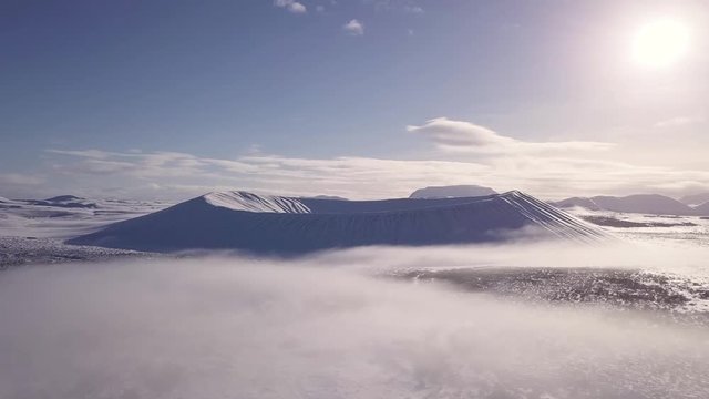 Drone footage from the volcano crater Hverfjall in Iceland during winter. Morning fog surrounds the crater.