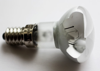 Broken incandescent light bulb on white background.
