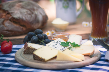 Verschiedenen Käsesorten serviert auf einem Holzbrett mit Trauben, Butter und Brot in einem Biergarten auf der Terrasse zum essen