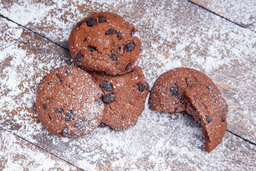 Shortbread cookies with chocolate chips on wooden background sprinkled with powdered sugar. Fresh pastry. Oatmeal cookies for Breakfast. Flat lay.