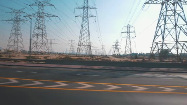 Traffic on a highway in Dubai, UAE. Sandy landscape and infrastructure with a blue sky.