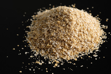 Large size oat bran, useful, cleansing, for a healthy diet on a black background