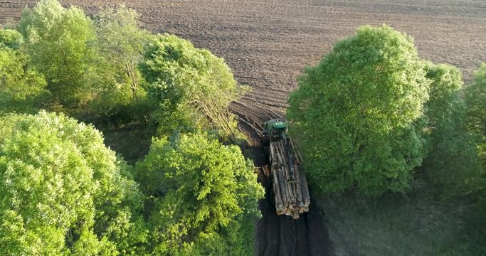 aerial-drone shot of forestry machine called forwarder that brings timber from forest to collection sites. Forwarder is with timber at the time and driving near trees.