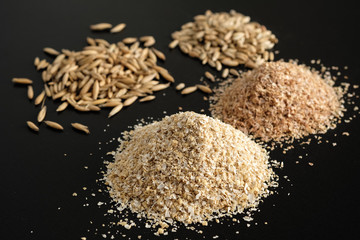 Bran oatmeal with a large grind, with grains of oats and wheat on a black background. Useful, cleansing, for a healthy diet