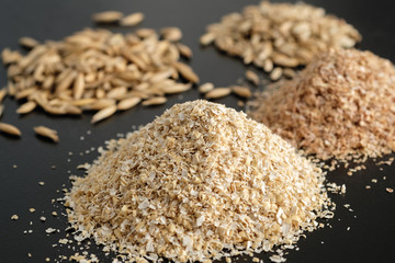Bran oatmeal with a large grind, with grains of oats and wheat on a black background. Useful, cleansing, for a healthy diet