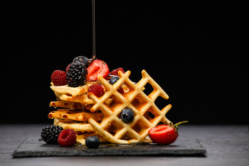 Photo of viennese wafers with berries pouring honey on black empty background