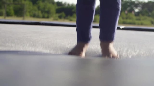 The feet of a girl / child jumping on a trampoline. With sunflare at Sunset / Sunrise.