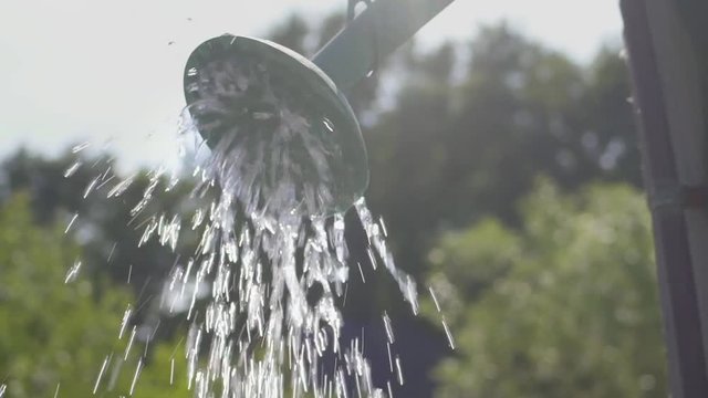 Clean and fresh water comes from the shower head at an outdoor garden shower. Normal Speed. Sunflare.