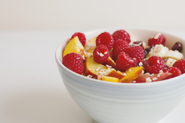 Oats with raspberry, sliced nectarine fruit, banana, plum and dried cranberry. Healthy breakfast