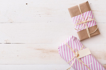 Top view on two Christmas or birthday gifts in craft paper and tag on white wooden background