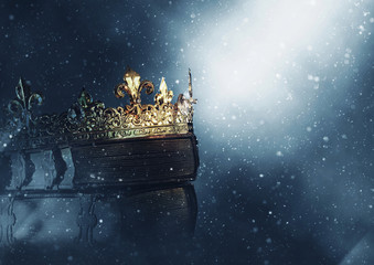 mysteriousand magical image of old crown and book over gothic black background. Medieval period...