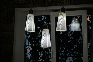 A white decorative lamp hangs from the ceiling. A modern chandelier in the kitchen.