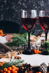 Mulled wine in glasses ,red berries,bumps and autumn branches on wooden table. Autumn or Winter concept.