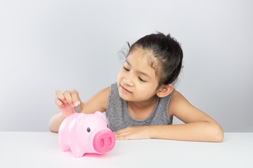 Cute asian girl putting coin into piggy bank saving money for her future concept for financial