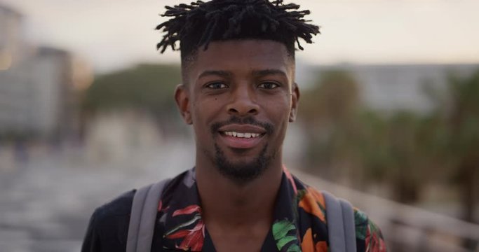 portrait happy african american man smiling cheerful attractive black tourist enjoying summer vacation travel looking relaxed funky hairstyle slow motion