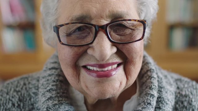 close up portrait of beautiful elderly woman looking laughing happy at camera wearing glasses