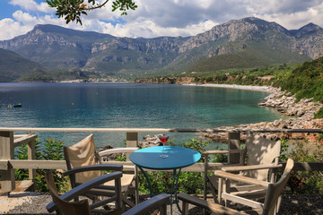 A glass of red martini on the table in the resort bar on the background of a picturesque seascape, summer vacation concept.