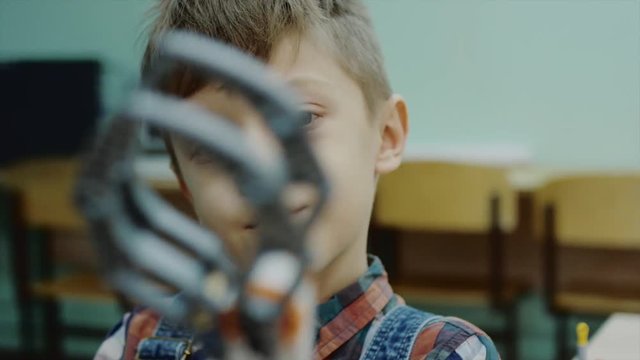 Close up shot of a wunderkind boy programming new robotic claw in a club. Excited smart boy designed robotic claw.