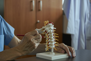 A neurosurgeon pointing at cervical spine model