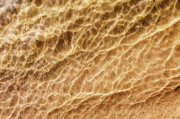 Soft wave of water on sandy beach, background.