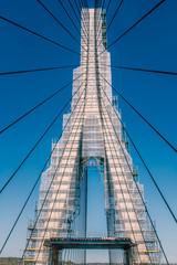 Fototapeta premium The International bridge, a suspension bridge between Spain and Portugal, crossing the Guadiana river covered in scaffolding during a repair, refurbishment