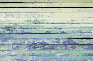 Vintage wood background with peeling yellow and turquoise old flaky paint. wall of an old house