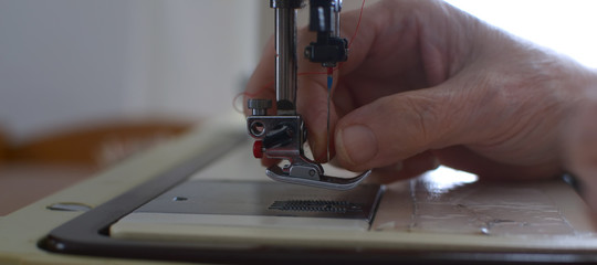 Seamstress tucks the yarn into the needle of the stain to sew 