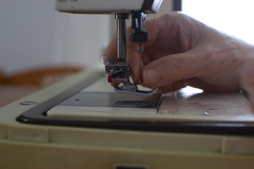 Seamstress tucks the yarn into the needle of the stain to sew 