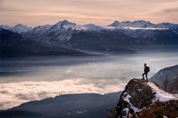 Man hiker looking mountain landscape with fog standing on a rock in Patagonia Argentina