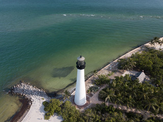 The restored Cape Florida Lighthouse on Biscayne Bay south of Miami Florida and the clear gorgeous waters and reefs as seen from above via drone