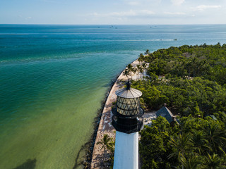 The restored Cape Florida Lighthouse on Biscayne Bay south of Miami Florida and the clear gorgeous waters and reefs as seen from above via drone