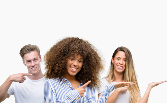 Group of young people over white background very happy pointing with hand and finger