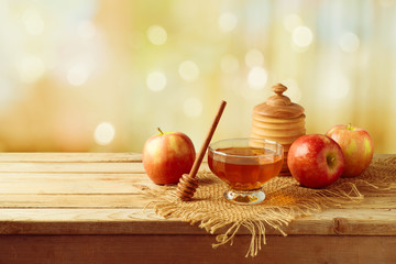 Honey and apples on wooden table.