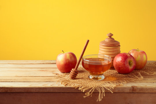 Honey and apples on wooden table