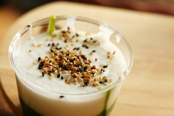 Green coconut sweet pudding in plastic cup scene.