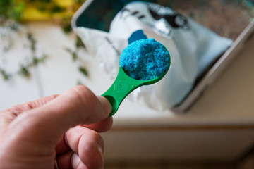 Blue plant fertiliser on a green spoon prior to being mixed with water