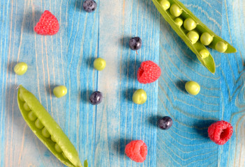 peas and berries on a blue wooden background