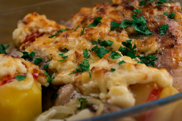 Chicken meat, baked with vegetables and cheese under a ruddy crust, sprinkled with chopped parsley.