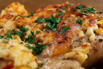 Chicken meat, baked in the oven with cheese and vegetables, decorated with finely chopped parsley.