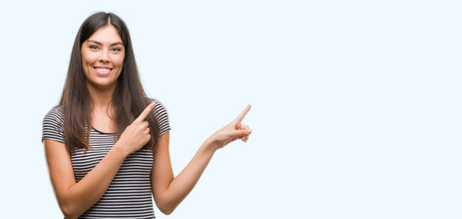 Young beautiful hispanic woman smiling and looking at the camera pointing with two hands and...