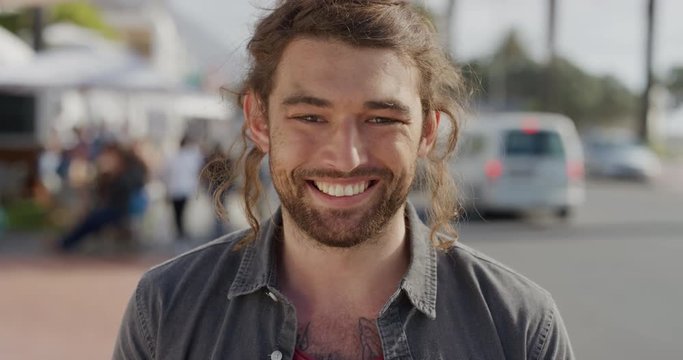 portrait of happy young man smiling enjoying carefree vacation lifestyle looking cheerful independent male on warm sunny urban beachfront