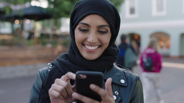 portrait of young beautiful muslim woman using smartphone laughing cheerful at social media messages
