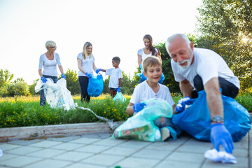 Volunteers with garbage bags cleaning up garbage outdoors - ecology concept.