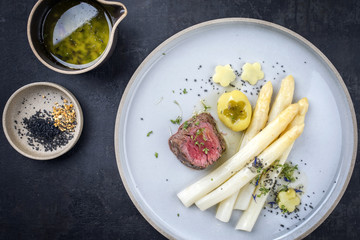 Modern Style deutsches Barbecue Rinderfilet Steak aufgeschnitten mit weissen Spargel asparagus und Bratkartoffel in Butter Sauce als Draufsicht auf Teller 