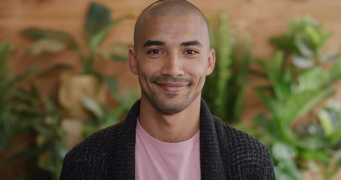 portrait of attractive young middle eastern man smiling enjoying happy lifestyle looking at camera plants background slow motion